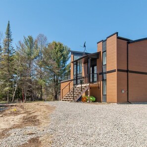A modern two-story building with a gravel driveway and a staircase leading to the entrance.
