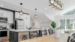 Una cocina moderna con una isla central, electrodomésticos de acero inoxidable y un comedor con mesa y sillas de madera.