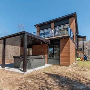 A modern two-story house with a covered patio area and a hot tub. - Vrbo Property (Saint-Alphonse-Rodriguez)