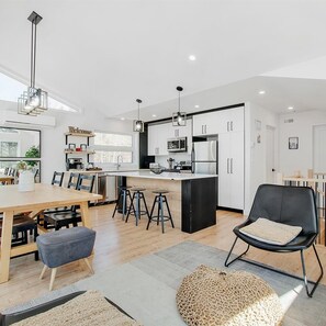 A modern kitchen with white cabinets, a central island, and bar stools. - Chalet le ZÖR | On the Lakeshore (Saint-Alphonse-Rodriguez)