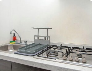 A kitchen with a sink, faucet, soap dispenser, dish rack, and gas stove. - Casa Santiago. Loft in the heart of the city center 3 (San Pedro Garza García)