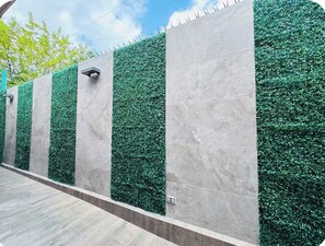 A wall with alternating vertical panels of artificial green foliage and smooth grey tiles. - Casa Santiago. Loft in the heart of the city center 3 (San Pedro Garza García)