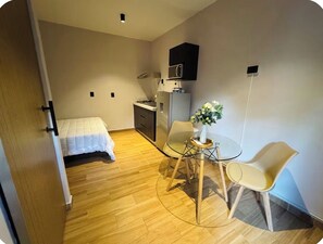 A compact room with a bed, a small kitchenette, a dining table with chairs, and a potted plant. - Casa Santiago. Loft in the heart of the city center 3 (San Pedro Garza García)