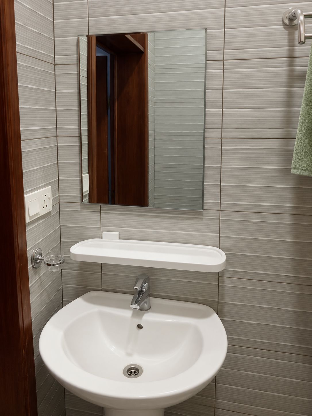 Ein Badezimmer mit einem weißen Waschbecken, einem Spiegel darüber und einem Handtuch an der Wand.