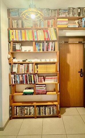Una libreria piena di libri e DVD, una porta di legno e un lampadario.