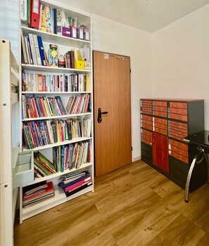Een kamer met een boekenkast vol boeken, een houten deur en een archiefkast met lades.