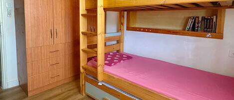 A bunk bed with a pink mattress and a wooden headboard.