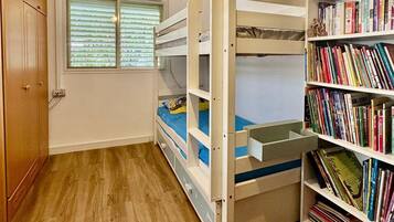 A room with a bunk bed, a bookshelf, and an air conditioning unit.
