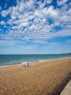 A pebbled beach with a person sunbathing, a clear sky, and calm sea. - Seafront Luxury apartment-sea view-Sleeps 5 (Minster On Sea)