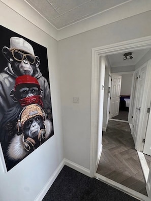 A hallway with a large wall mural of a monkey wearing a hat and headphones.