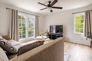 Una sala de estar con un sofá, televisión y ventilador de techo.