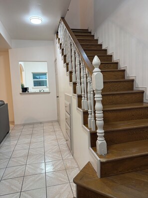 A staircase with wooden steps and white balusters, leading to an upper floor. - Charming 2-bedroom townhome with pool and other HOA amenities (Pharr)