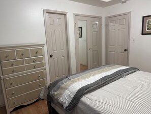 A bedroom with a bed, a dresser, and two doors. - Charming 2-bedroom townhome with pool and other HOA amenities (Pharr)