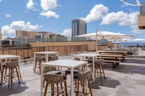 Een terras met tafels, stoelen en parasols, met uitzicht op de skyline van de stad.