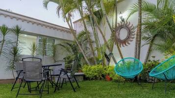 Pátio com móveis de exterior, um espelho decorativo fixado na parede e diversas plantas.