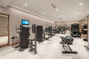 A modern gym with various exercise equipment, including a treadmill, weight machines, and a rowing machine. - Elegant One-Bedroom Retreat (London)