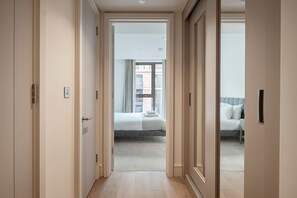 A hallway leading to a bedroom with a bed and a window. - Elegant One-Bedroom Retreat (London)