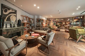 A spacious living room with a fireplace, comfortable seating, and a large window offering a view. - Elegant One-Bedroom Retreat (London)
