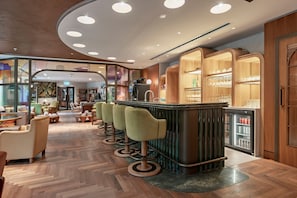 A modern bar area with a bar counter, stools, and a refrigerator stocked with beverages. - Stylish Two-Bedroom Residence (London)