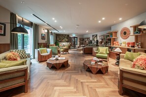 A spacious lounge area with multiple seating options, a central coffee table, and a bookshelf filled with books and decorative items. - Stylish Two-Bedroom Residence (London)