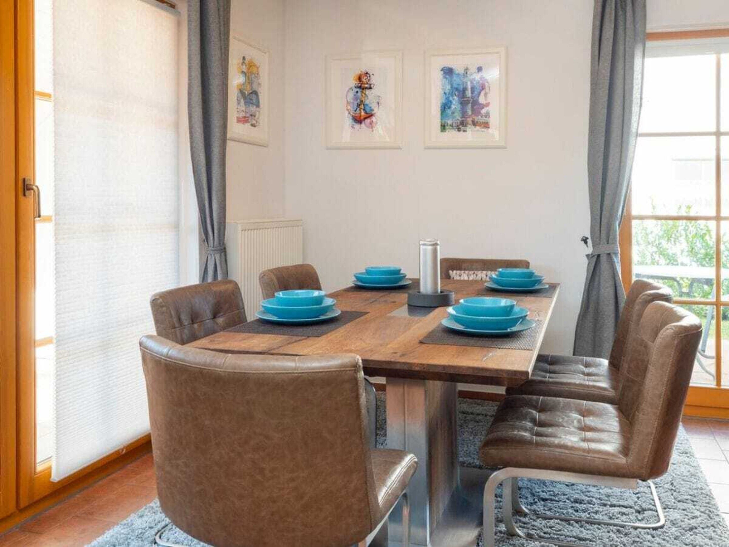 A dining area with a wooden table, blue plates, and brown leather chairs.