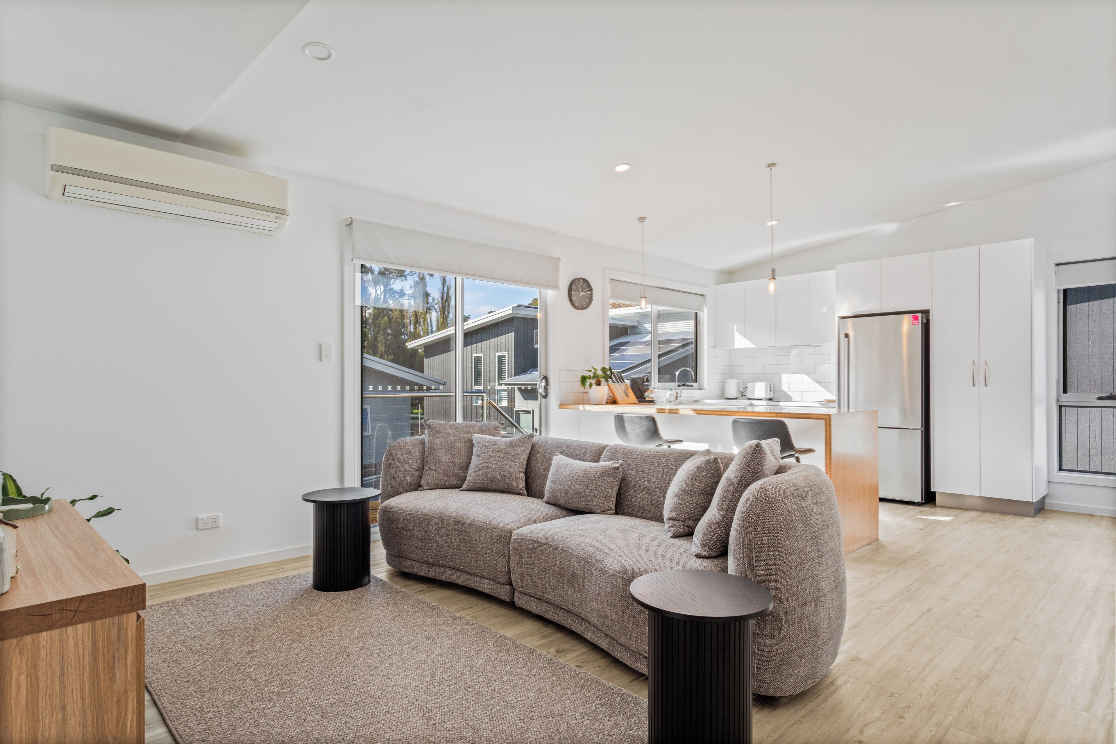 Sink into the plush sofa with a movie on the wall-mounted TV, while abundant daylight and soft neutral tones give the open-plan setting a fresh contemporary feel.