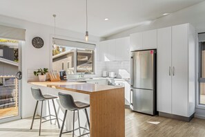 A modern kitchen with a central island, stainless steel appliances, and a large window. - Invermay Escape Stay Close to Stadium and Museums (Invermay)