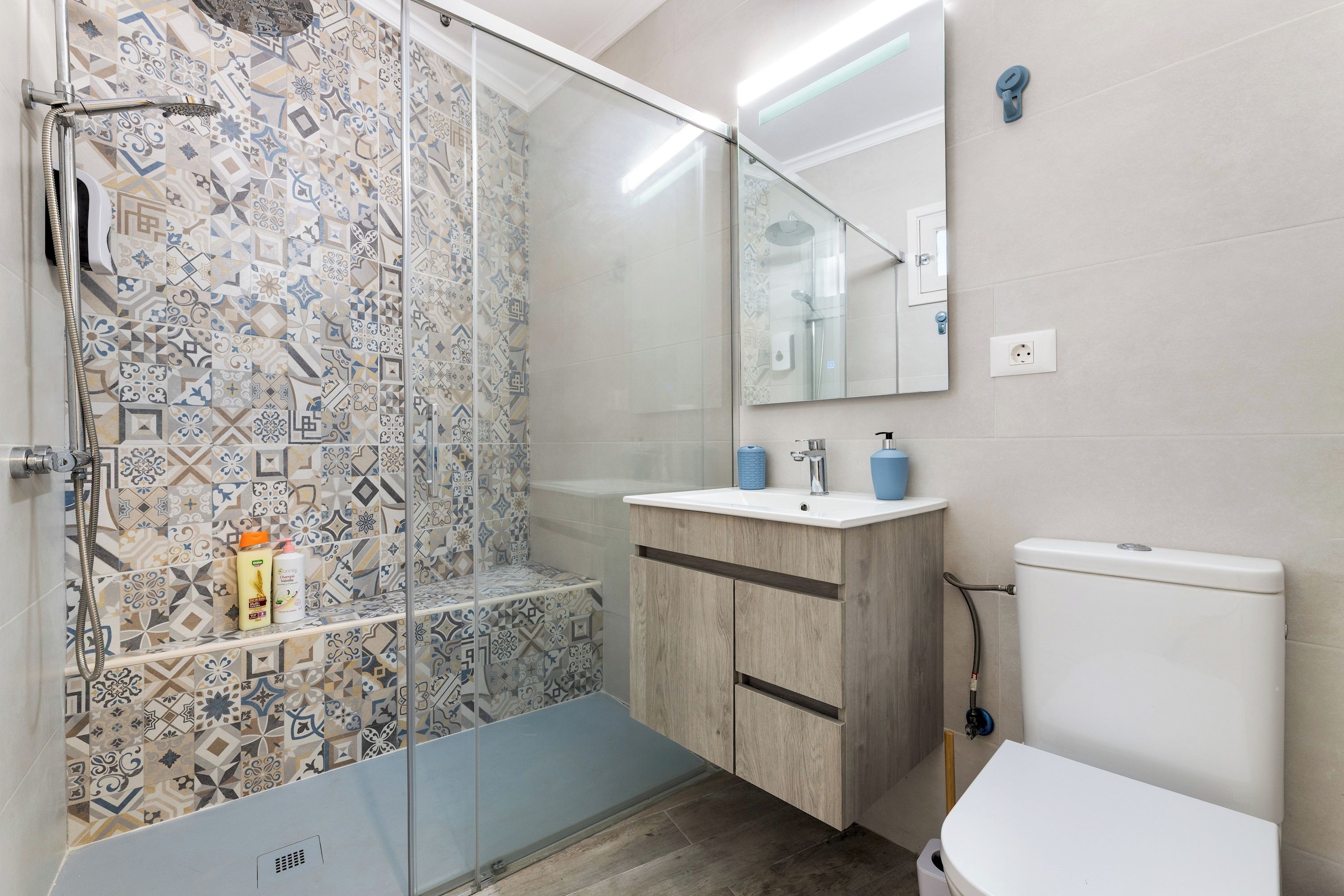 Ein Badezimmer mit Dusche, Waschbecken, Toilette und Spiegel.