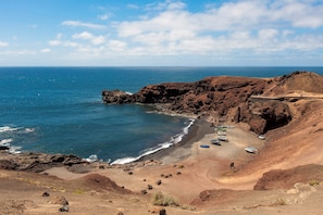 A coastal landscape with rocky terrain, a beach, and boats. - Home2Book Casa Yoyo Lanzarote Coastal Home (El Golfo)