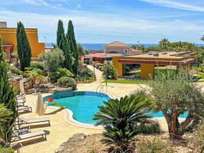 Ein Resort mit Swimmingpool, Liegestühlen und Meerblick.