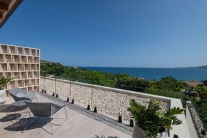 Un balcon avec vue sur la mer, un coin salon avec des chaises et une structure en bois.