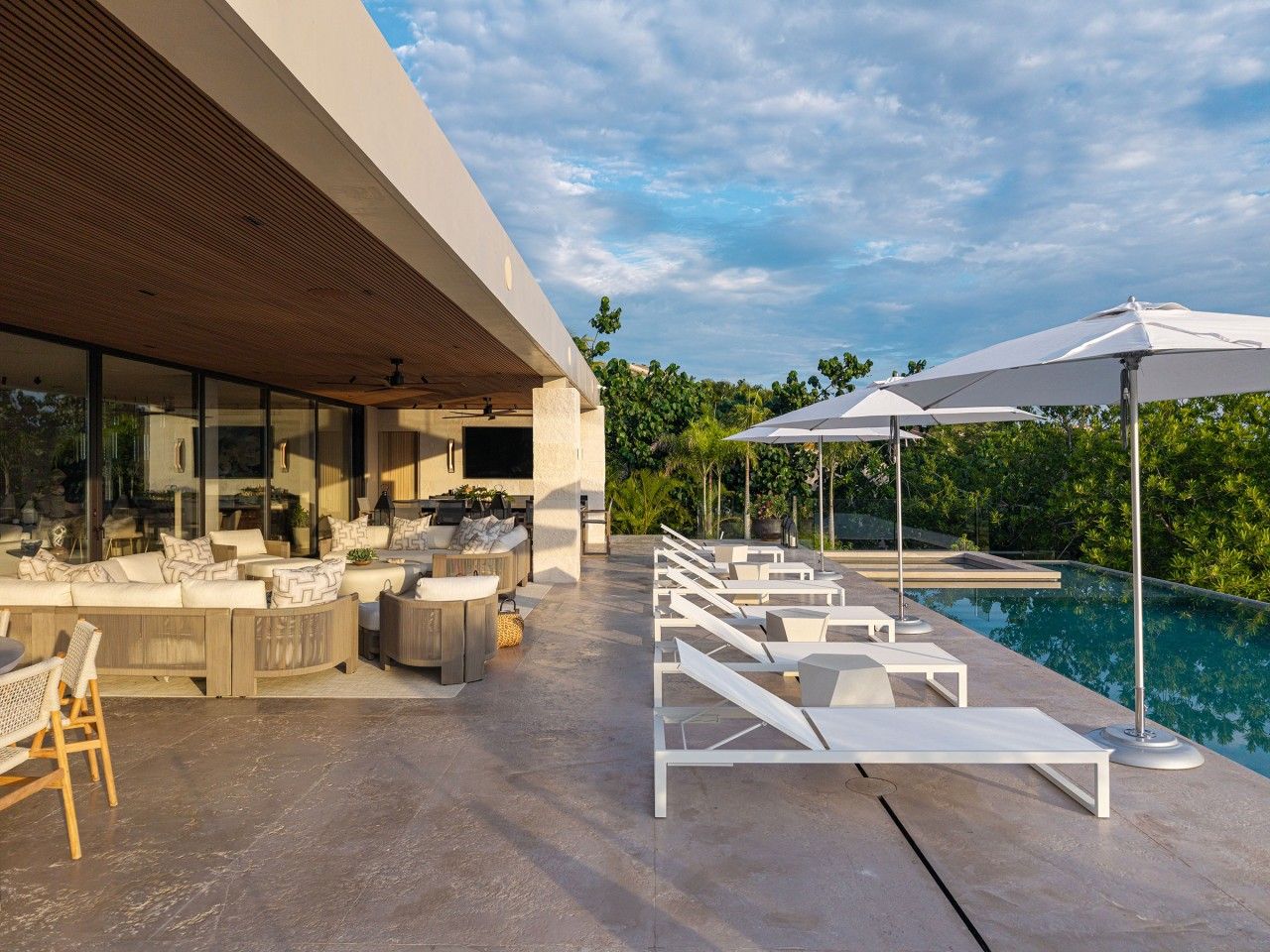 A modern outdoor lounge area with a pool, seating, and umbrellas.