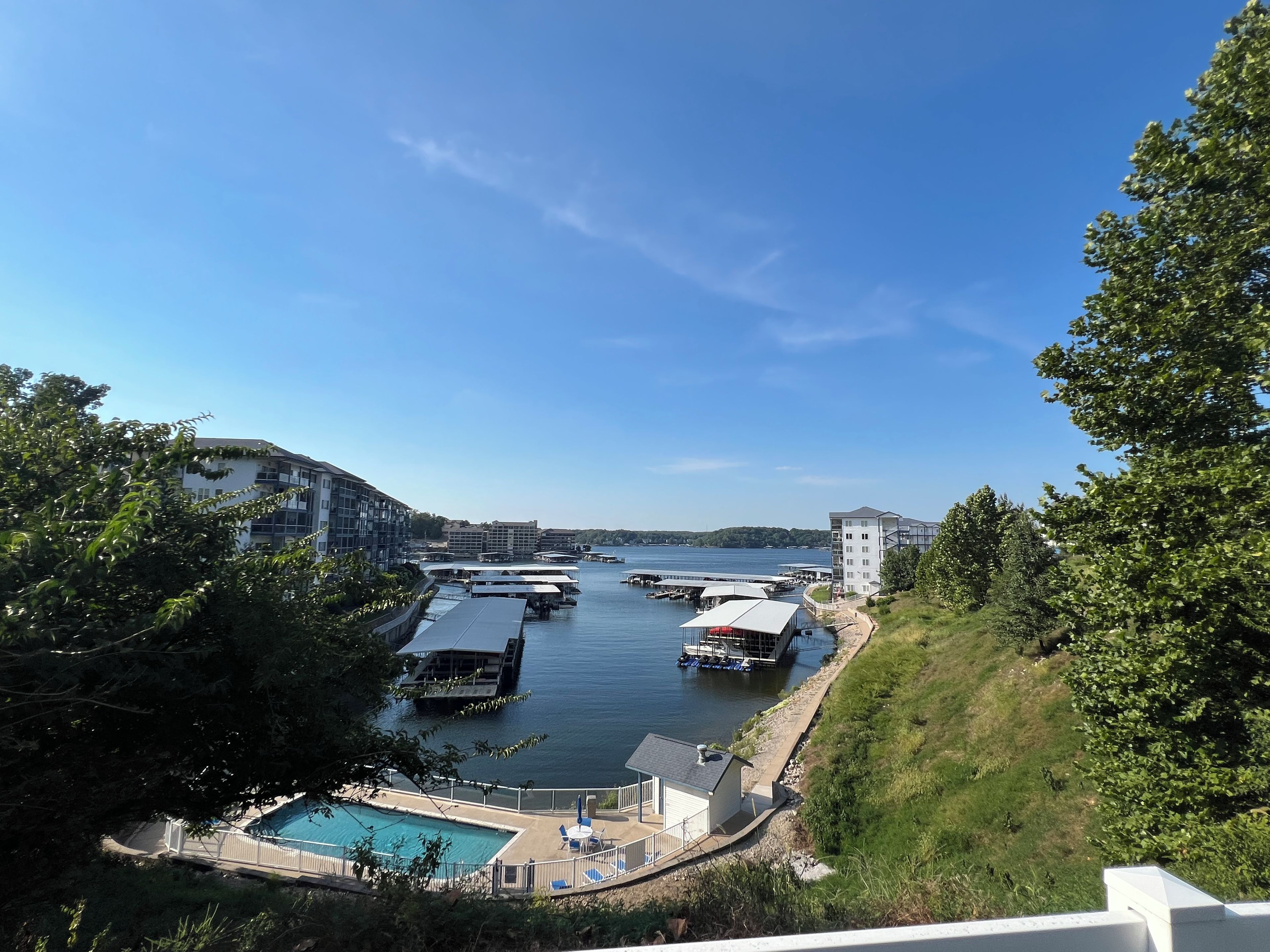 A marina with boats docked, a swimming pool, and buildings in the background.