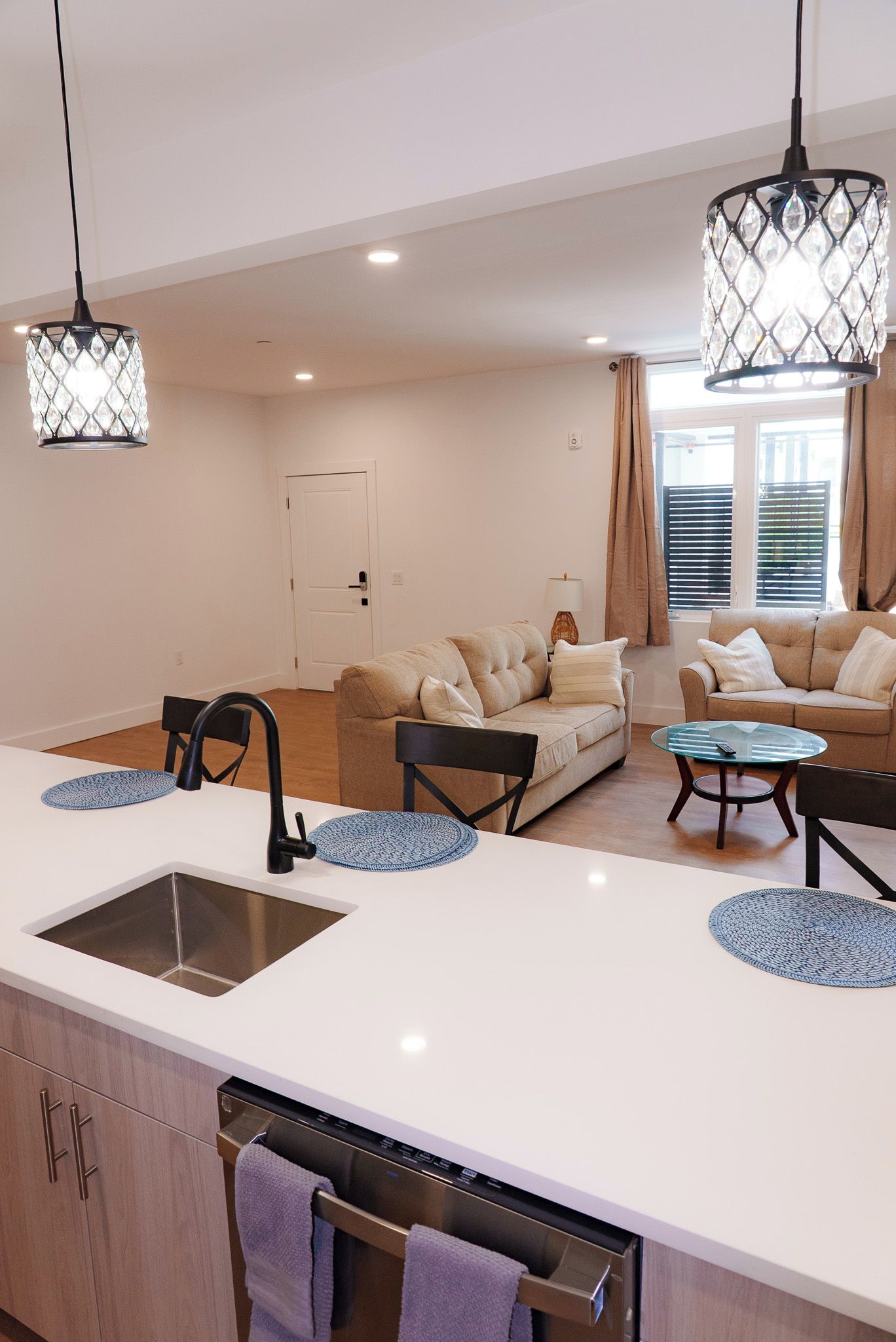 A modern kitchen with a central island, a dining area with a sofa and chairs, and a living area with a sofa and a coffee table.
