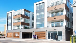 Un edificio residencial de varios pisos con garaje, un letrero que dice 'Coral Sands Condominium' y una señal de estacionamiento.