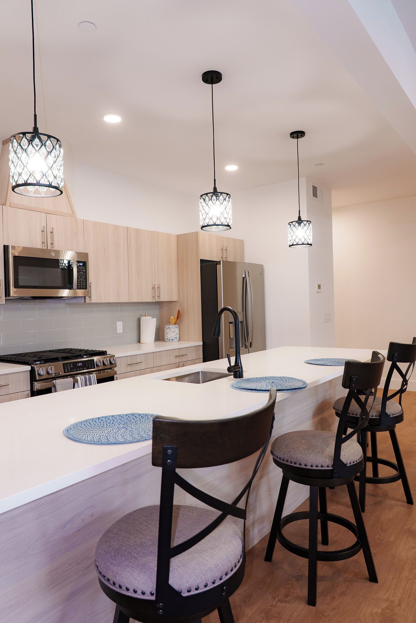A modern kitchen with a central island, stainless steel appliances, and pendant lighting.