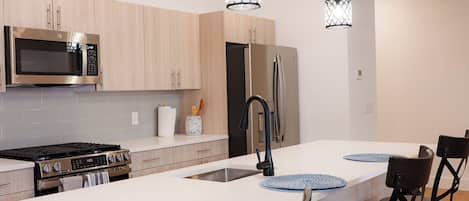 A modern kitchen with a central island, stainless steel appliances, and pendant lighting.