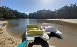 Una playa con una fila de barcos y un edificio al fondo.