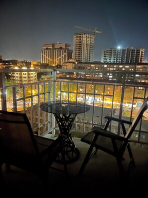 A balcony with a table and chairs, overlooking a cityscape with buildings and a construction crane. - Holiday Inn Apart on Buzand st. (Yerevan)