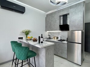 A modern kitchen with a built-in island, stainless steel appliances, and green bar stools. - Holiday Inn Apart on Buzand st. (Yerevan)