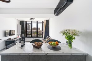 A modern kitchen with a marble countertop, a dining area with a table set for two, and a large window with a view of buildings. - Holiday Inn Apart on Buzand st. (Yerevan)