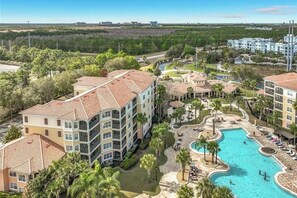 Un resort con edificios de varias plantas, una piscina central y abundante vegetación circundante.