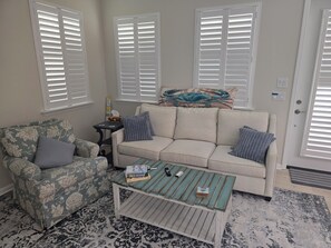 A living room with a sofa, armchair, coffee table, and a patterned rug.