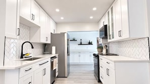 A modern kitchen with white cabinetry, a black faucet, and a built-in oven.