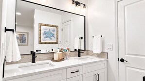 A bathroom with two sinks, a large mirror, and a towel rack.
