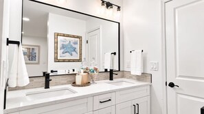 A bathroom with two sinks, a large mirror, and a towel rack.