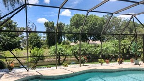 A swimming pool with a clear blue water, surrounded by a metal fence and lush greenery. - Gulf Tranquility in Rotonda West (Rotonda West)