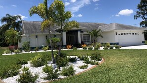 A residential house with a well-maintained lawn, a small tree, and a garage. - Gulf Tranquility in Rotonda West (Rotonda West)