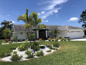 A residential house with a well-maintained lawn, a small tree, and a garage.