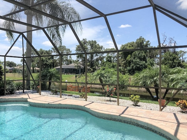 A swimming pool with a clear view of the surrounding landscape, including trees and a distant building.